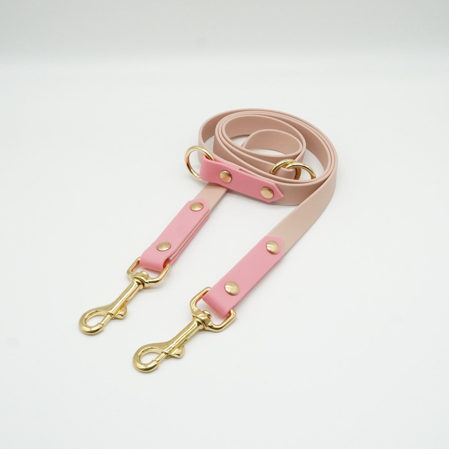 Handgefertigte verstellbare Hundeleine aus rosa und beiger Biothane mit goldfarbenen Messingbeschlägen und Karabinern.