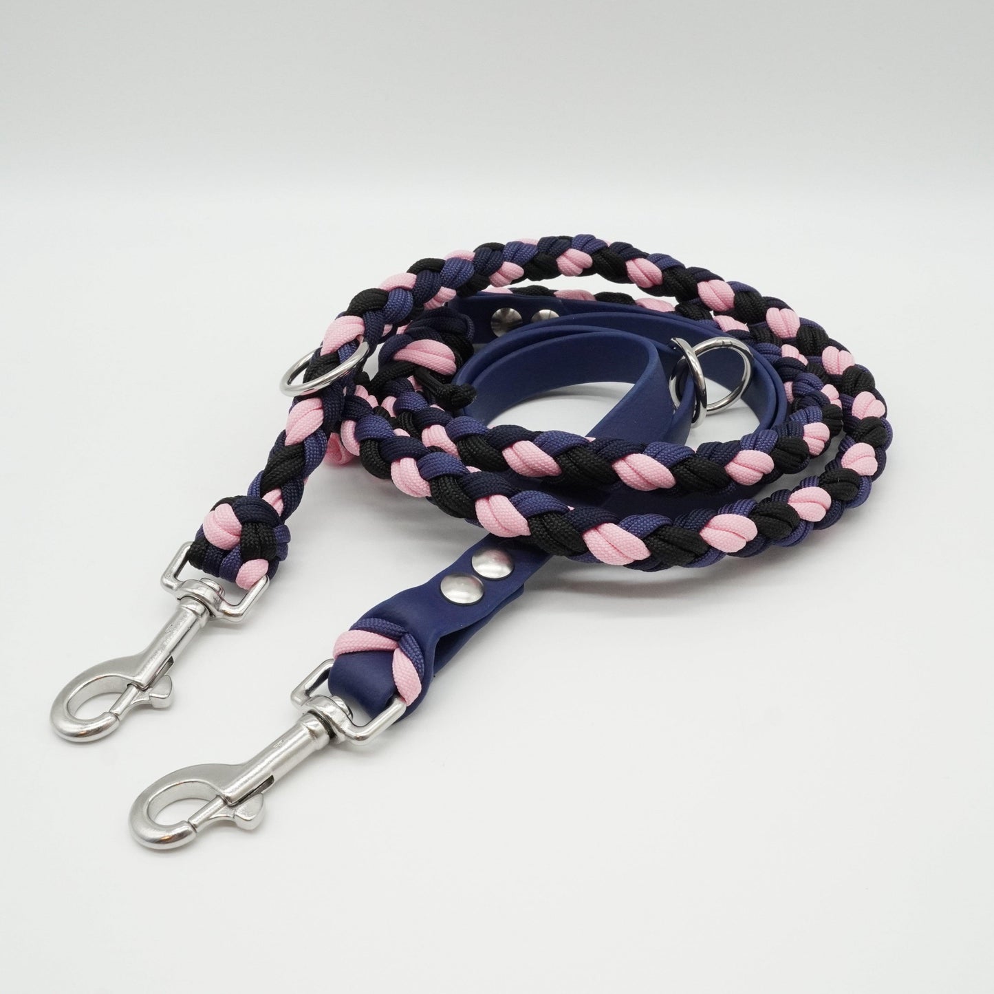 Handgefertigte verstellbare Hundeleine aus dunkelblauer Biothane und geflochtenem Paracord in Dunkelblau, Schwarz und Rosa mit silbernen Karabinern.